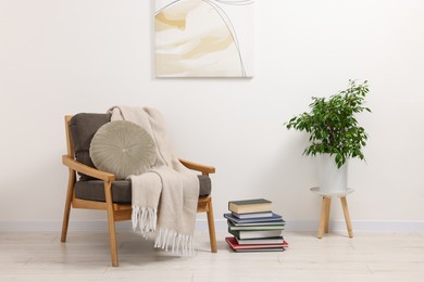 Photo of Stylish living room interior with comfortable armchair, blanket and houseplant