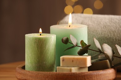 Spa composition. Burning candles, soap, towel and eucalyptus branch on wooden table