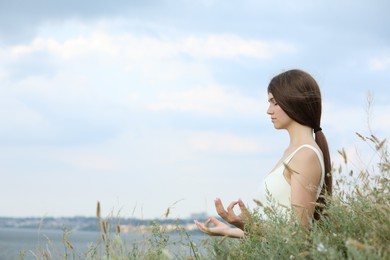 Photo of Teenage girl meditating outdoors. Space for text
