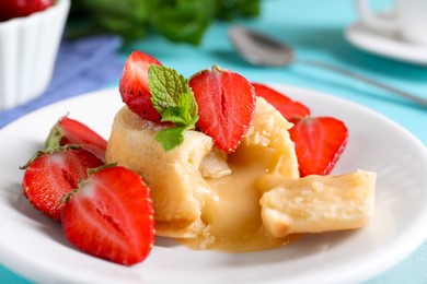 Photo of Tasty vanilla fondant with white chocolate and strawberries on table, closeup
