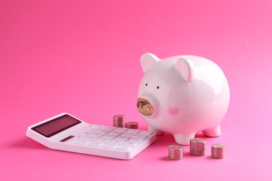 Financial savings. Piggy bank, coins and calculator on pink background