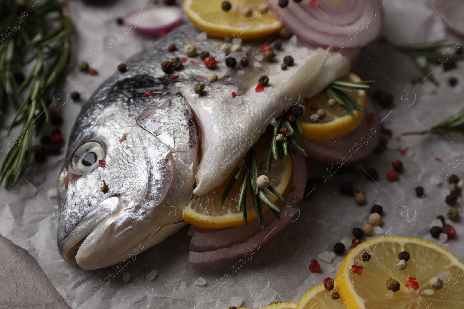 Photo of Fresh raw dorado fish with spices, lemon and onion on table, closeup