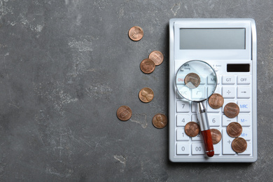 Photo of Calculator, magnifying glass and coins on grey stone table, flat lay with space for text. Search concept