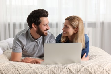 Photo of Happy couple with laptop on bed at home