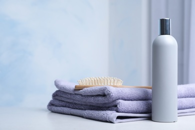 Photo of Bottle with shampoo, towels and brush on table, space for text