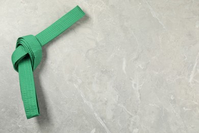 Green karate belt on gray marble background, top view. Space for text