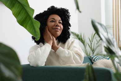 Relaxing atmosphere. Woman surrounded by beautiful houseplants indoors