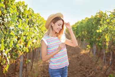 Photo of Young beautiful woman with glass of wine at vineyard on sunny day