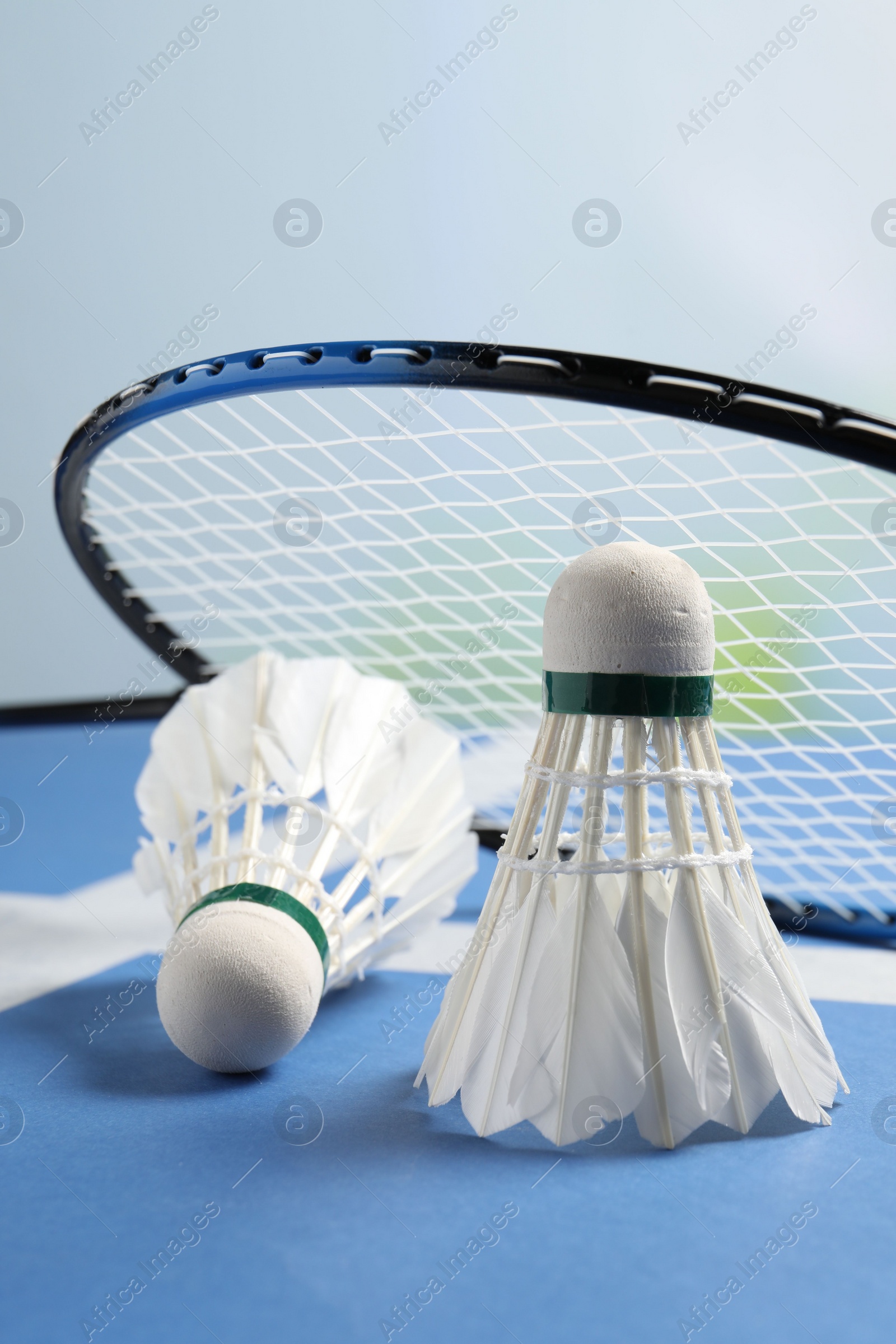 Photo of Feather badminton shuttlecocks and racket on blue table against blurred background, closeup