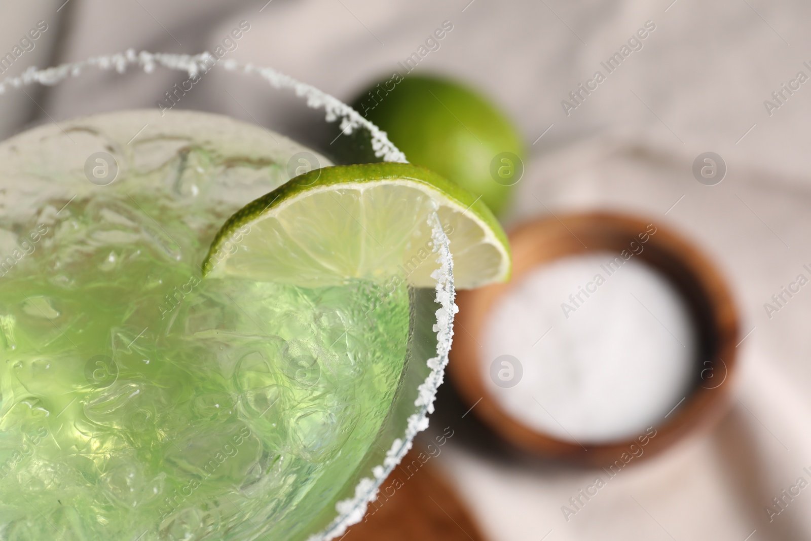 Photo of Delicious Margarita cocktail with ice cubes in glass and lime on table, closeup. Space for text