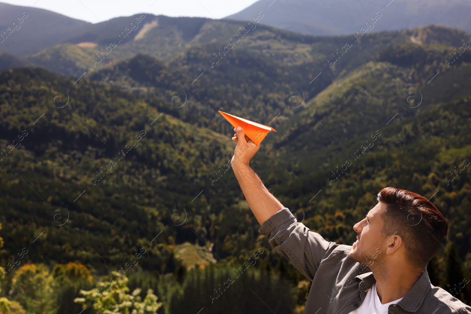 Photo of Man throwing paper plane in mountains on sunny day. Space for text