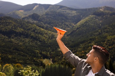 Photo of Man throwing paper plane in mountains on sunny day. Space for text
