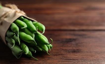 Photo of Fresh green beans on wooden table, closeup. Space for text