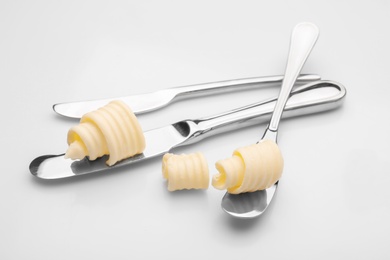 Utensils with butter curls on white background