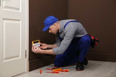 Photo of Professional male electrician repairing power socket indoors