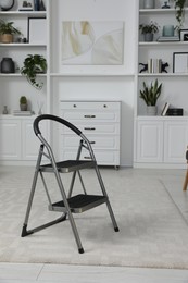 Metal folding ladder on soft carpet in stylish room