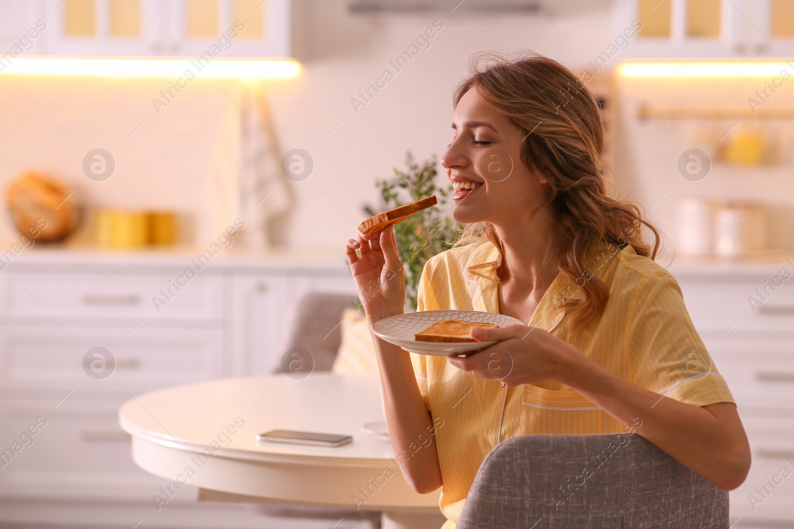 Photo of Beautiful young woman having breakfast in kitchen. Weekend morning