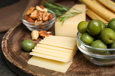Photo of Snack set with delicious Parmesan cheese on wooden plate, closeup