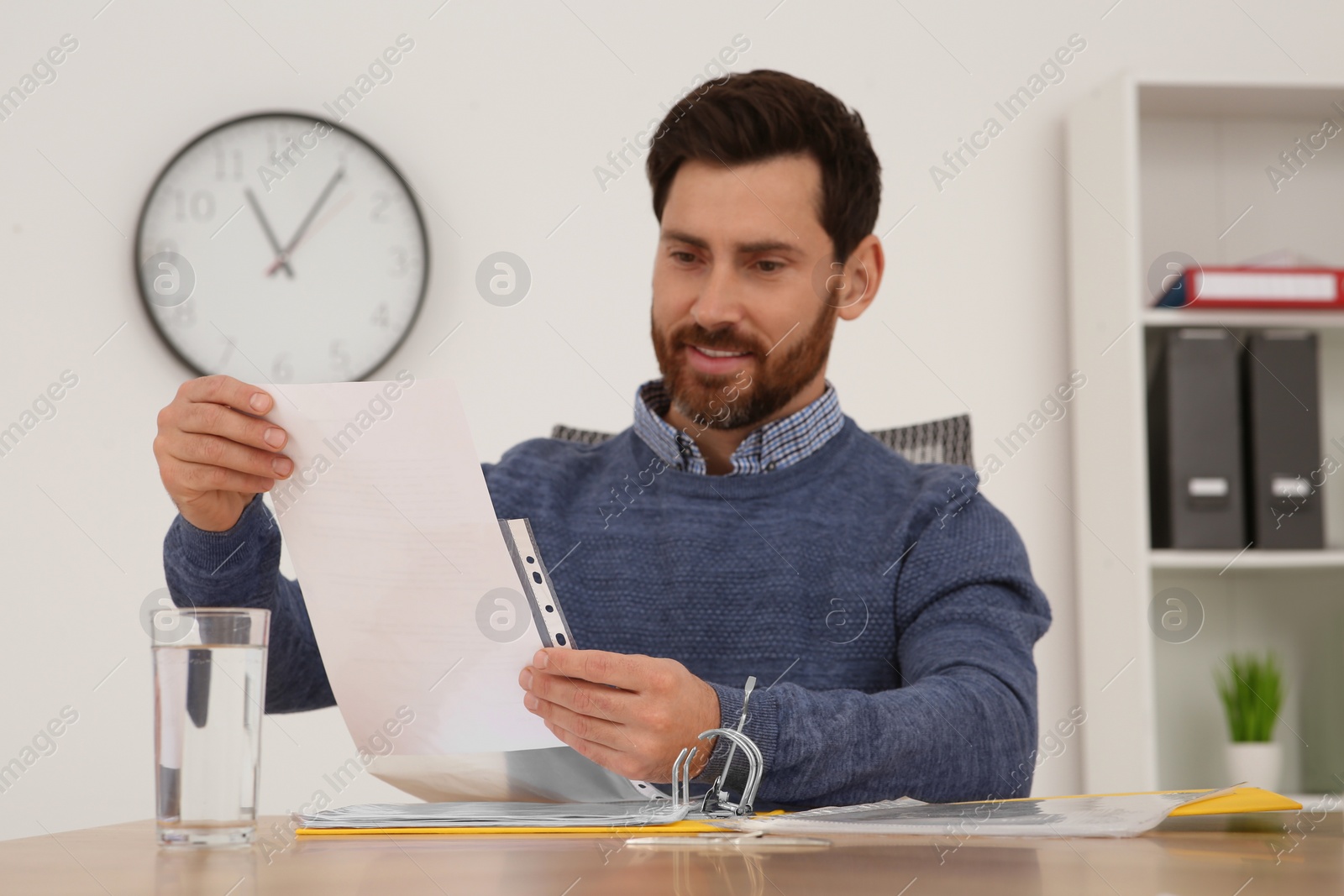 Photo of Businessman reading document at wooden table in office