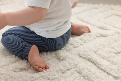 Photo of Baby sitting on soft carpet, closeup. Space for text