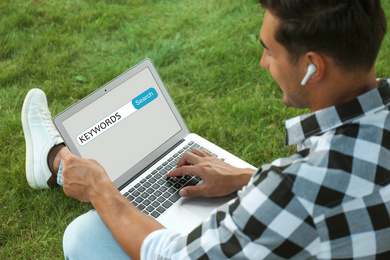 Man with laptop searching for keywords outdoors