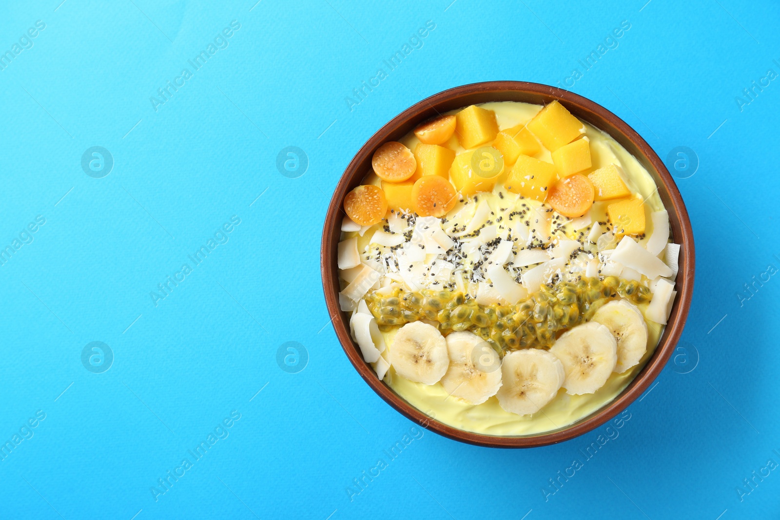 Photo of Tasty smoothie bowl with fresh fruits on light blue background, top view. Space for text