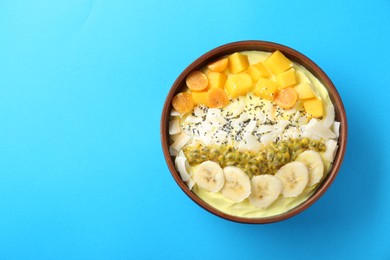 Photo of Tasty smoothie bowl with fresh fruits on light blue background, top view. Space for text