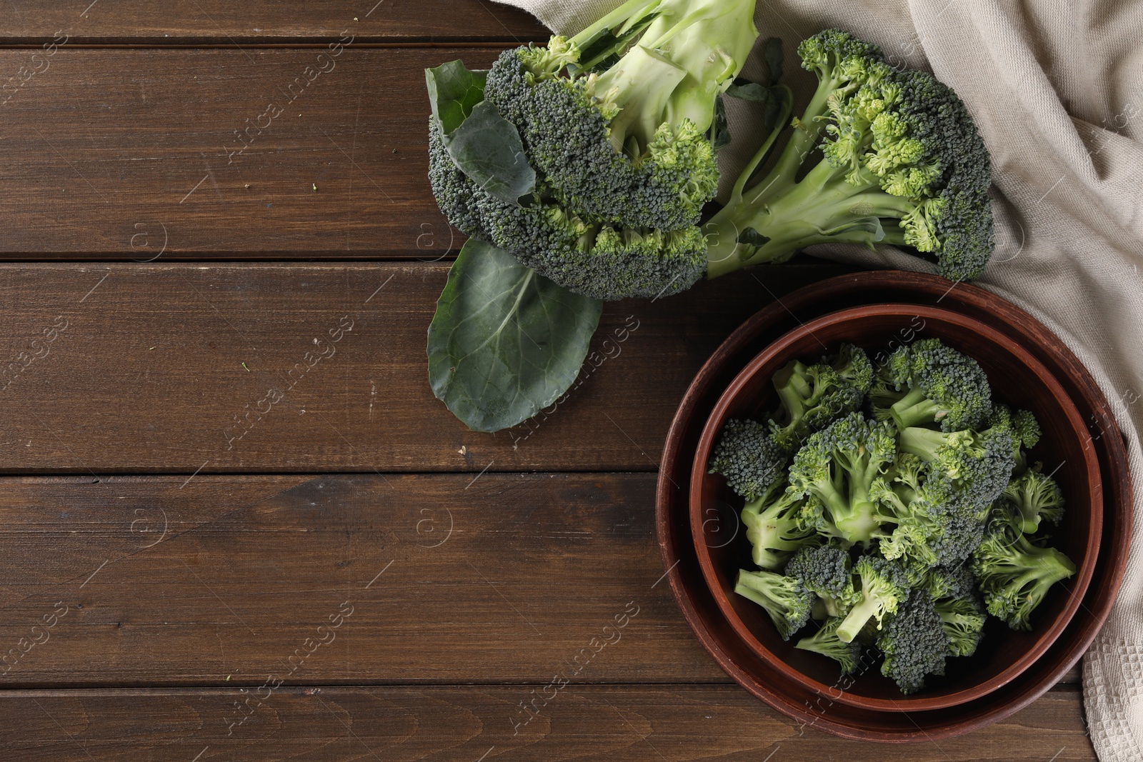 Photo of Bowl with fresh raw broccoli on wooden table, flat lay. Space for text