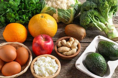 Photo of Healthy meal. Different vegetables and raw eggs on wooden table