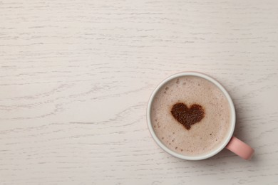Cup of aromatic coffee with heart shaped decoration on white wooden table, top view. Space for text