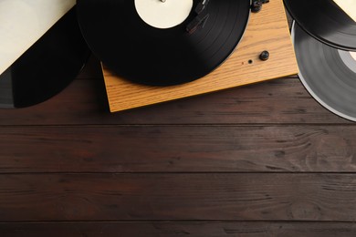 Photo of Vintage vinyl records and turntable on wooden background, flat lay. Space for text