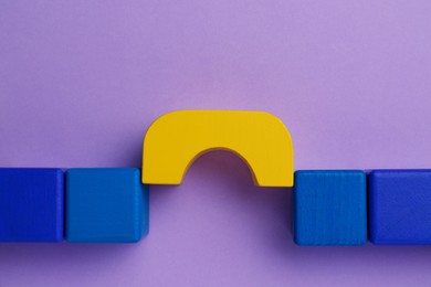 Photo of Bridge made of colorful blocks on violet background, flat lay. Connection, relationships and deal concept