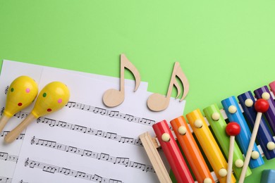 Photo of Tools for creating baby songs. Flat lay composition with maracas and xylophone on green background