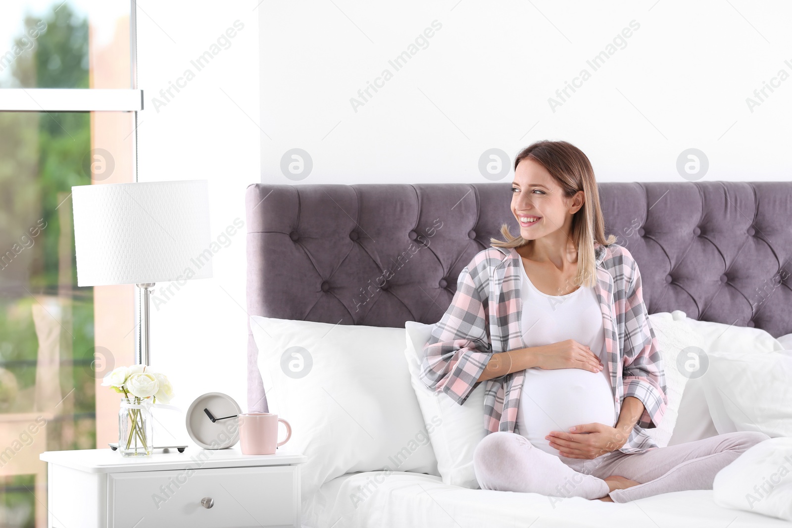 Photo of Happy pregnant woman sitting in bed at home