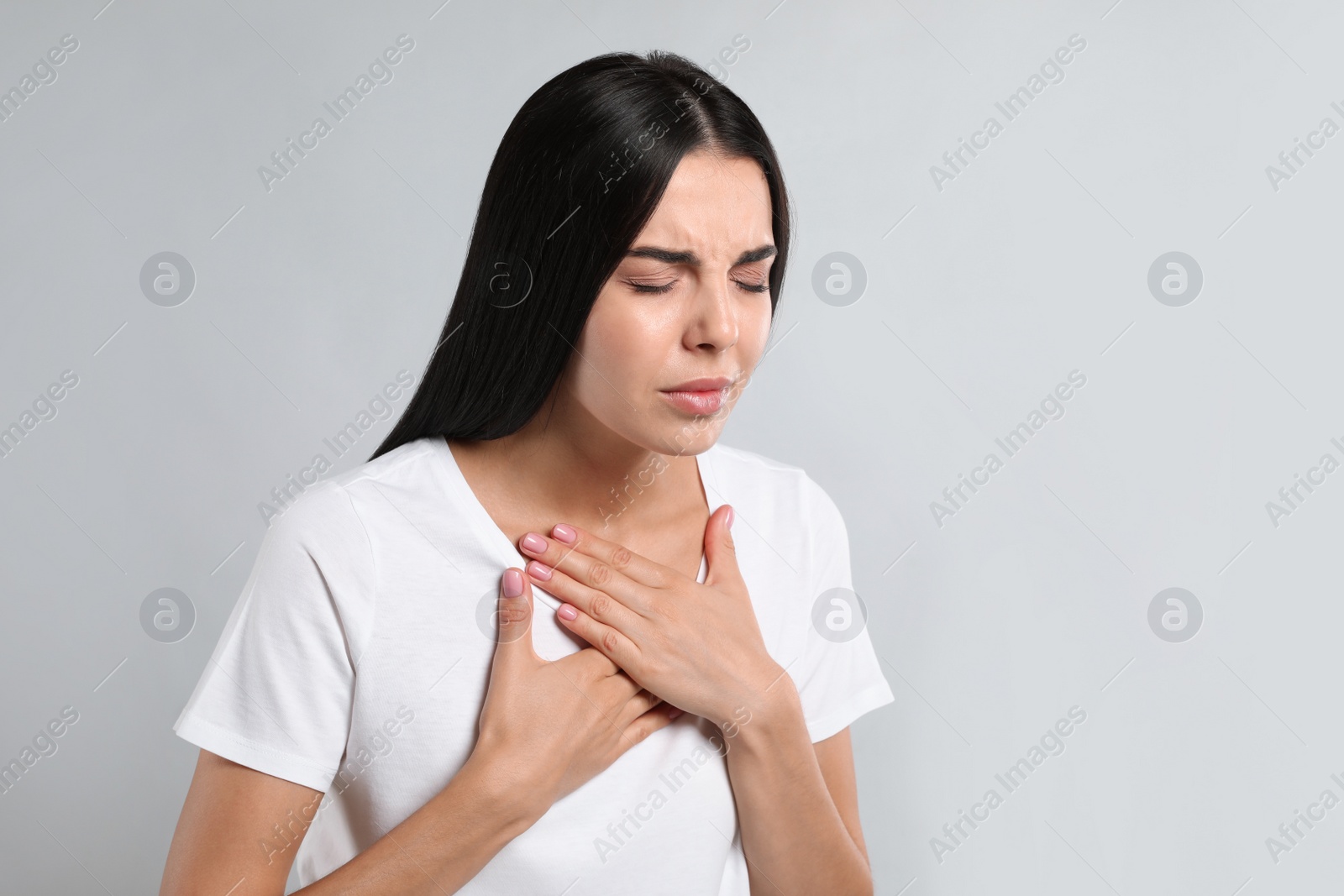 Photo of Young woman suffering from breathing problem on light background