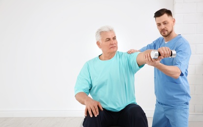 Photo of Young physiotherapist working with senior patient in clinic