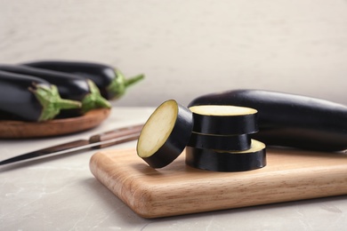 Photo of Wooden board with ripe eggplants on table