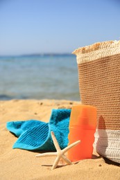 Sunscreen, starfish, bag and towel on beach. Sun protection care