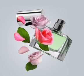 Bottle of perfume and roses in air on grey background. Flower fragrance