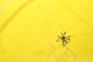 Photo of Cobweb and spider on yellow background, top view
