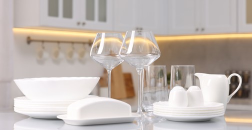 Set of clean dishware and glasses on table in kitchen