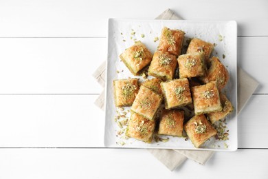 Photo of Delicious fresh baklava with chopped nuts on white wooden table, top view and space for text. Eastern sweets