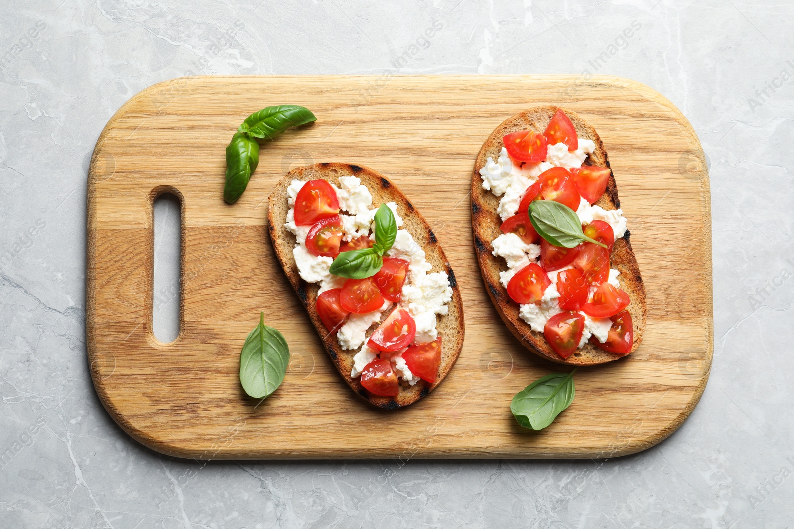 Photo of Board with tasty bruschettas on grey table, top view