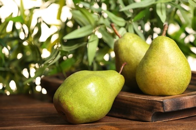 Photo of Fresh ripe pears on wooden table against blurred background