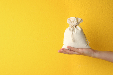 Photo of Woman holding full cotton eco bag on yellow background, closeup. Space for text