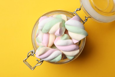 Photo of Jar of delicious colorful marshmallows on yellow background, top view