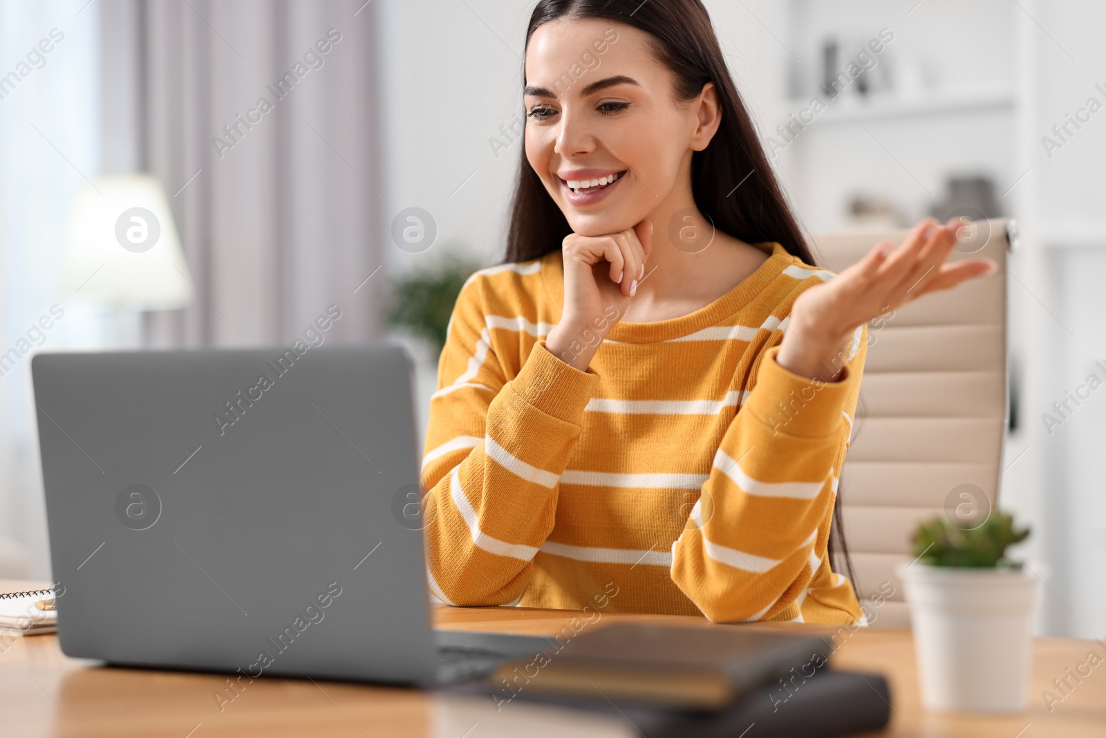 Photo of Young woman using video chat during webinar at table in room