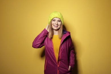 Photo of Young woman wearing warm clothes on color background. Ready for winter vacation