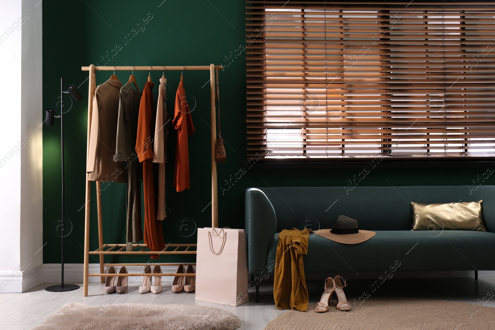 Photo of Modern dressing room interior with clothing rack and comfortable sofa