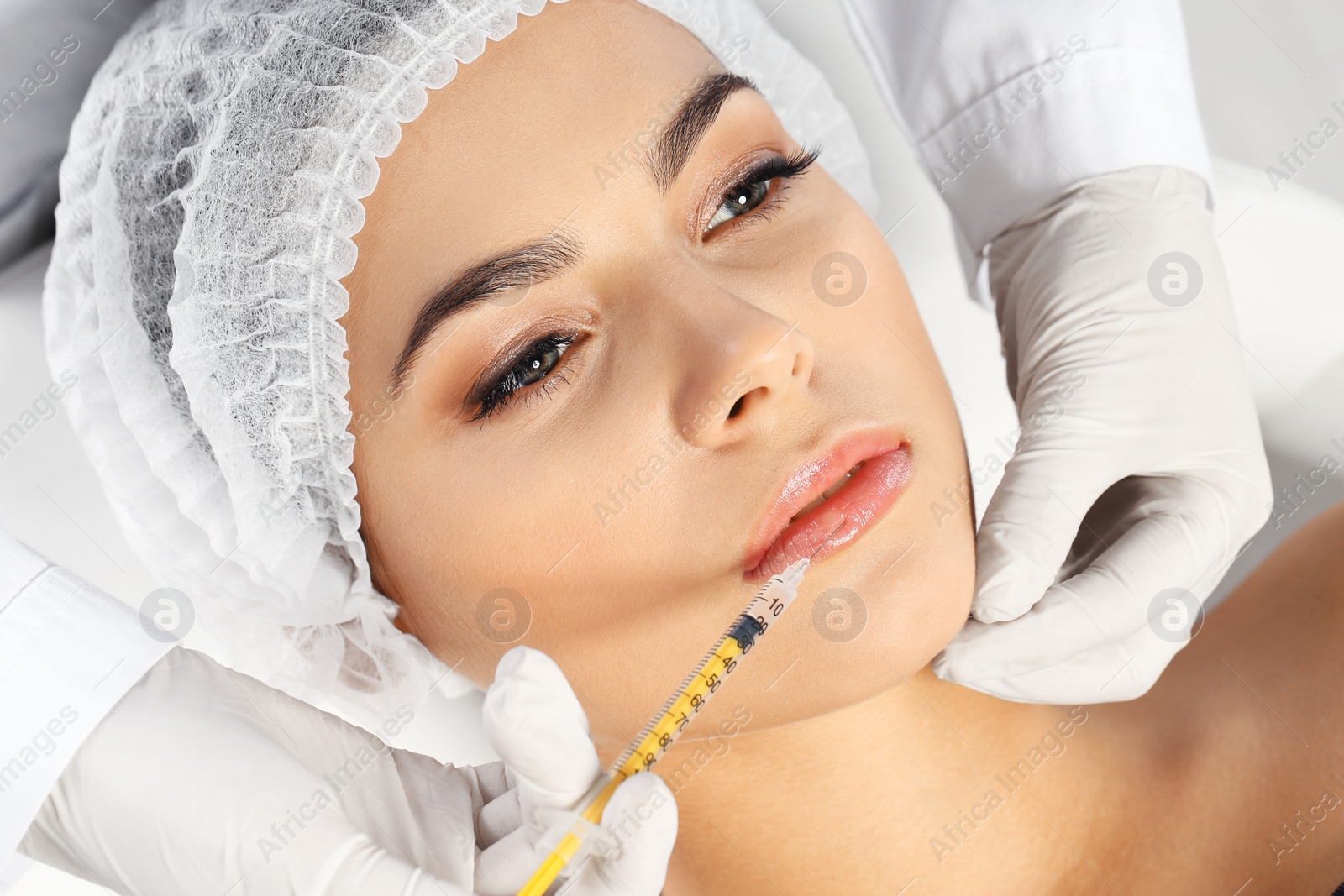 Photo of Young woman getting lips injection in clinic. Cosmetic surgery